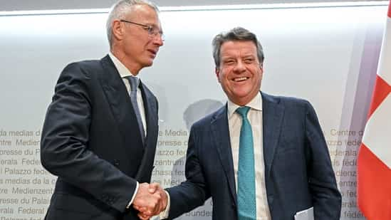 UBS Chairman Colm Kelleher (R) shakes hands with Credit Suisse chairman Axel Lehmann (L) after a press conference. (AFP)