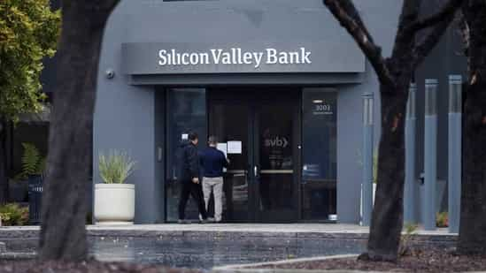 A man puts a sign on the door of the Silicon Valley Bank as an onlooker watches at the bank’s headquarters in Santa Clara, California(REUTERS)