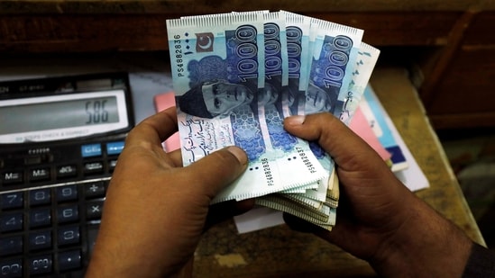 FILE PHOTO: A trader counts Pakistani rupee notes at a currency exchange booth(REUTERS)