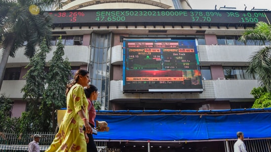 Market updates today: People walk past an electronic signage displayed at the Bombay Stock Exchange (BSE) building.(PTI)