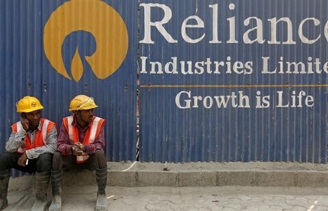 FILE PHOTO: Labourers rest in front of an advertisement of Reliance Industries Limited at a construction site in Mumbai.(REUTERS)