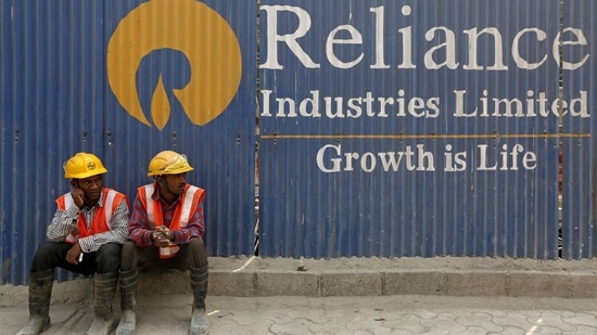 FILE PHOTO: Labourers rest in front of an advertisement of Reliance Industries Limited at a construction site in Mumbai.(REUTERS)