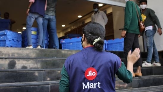 A woman wearing a Reliance JioMart vest instructs workers as they stock their products inside a Future Retail's closed Big Bazaar retail store in Mumbai.(Reuters / File)