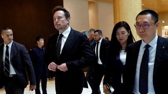 Tesla chief executive officer Elon Musk walks next to Tesla's Senior Vice President Tom Zhu and Vice President Grace Tao as he leaves a hotel in Beijing, China(REUTERS)