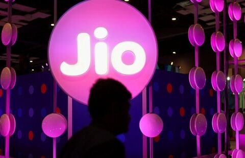 A man walks across the LED board showing the logo of Jio(REUTERS)