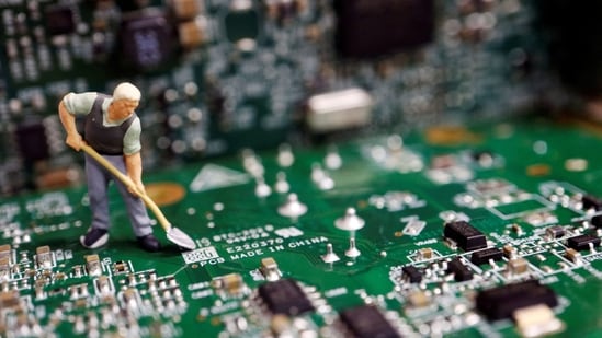 A worker miniature is placed among printed circuit boards with semiconductor chips.(REUTERS)