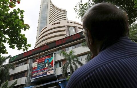 A man looks at a screen across a road displaying the Sensex on the facade of the Bombay Stock Exchange (BSE) building in Mumbai.(REUTERS)