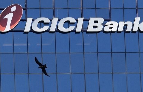 A bird flies past the facade of the ICICI bank head office in Mumbai (Reuters)