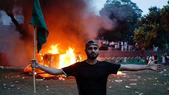 Marico share price: A man holding a Bangladesh flag stands in front of a vehicle that was set on fire at the Ganabhaban, the Prime Minister's residence, after the resignation of PM Sheikh Hasina in Dhaka, Bangladesh.(Reuters)