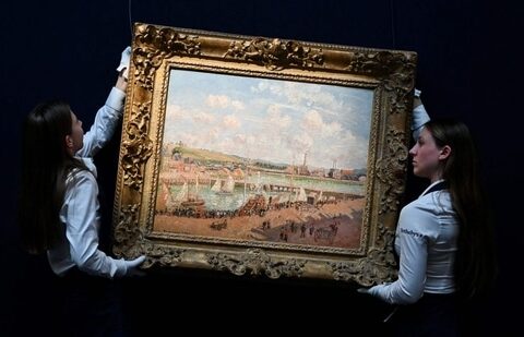 Two members of staff hold the painting by late Franco-Danish painter Camille Pissaro "Darse de peche et bassin Duquesne, Dieppe, apres-midi ensoleillee" (Fishing dock and Duquesne basin, Dieppe, sunny afternoon) during the photocall at the Sotheby's auction house, in central London, on June 19, 2024 ahead of the Sotheby's major Modern & Contemporary art auction of the summer season. (Justin Tallis/AFP)(AFP)