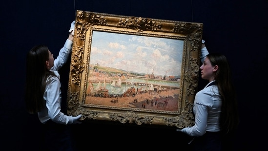 Two members of staff hold the painting by late Franco-Danish painter Camille Pissaro "Darse de peche et bassin Duquesne, Dieppe, apres-midi ensoleillee" (Fishing dock and Duquesne basin, Dieppe, sunny afternoon) during the photocall at the Sotheby's auction house, in central London, on June 19, 2024 ahead of the Sotheby's major Modern & Contemporary art auction of the summer season. (Justin Tallis/AFP)(AFP)