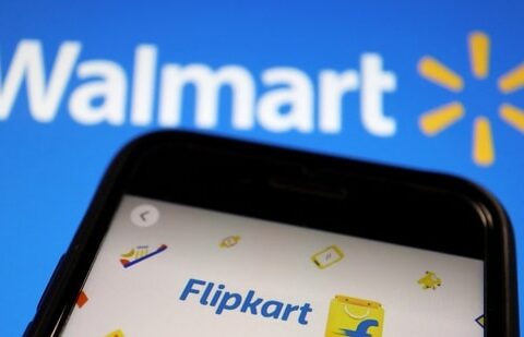 Latest news on August 16, 2024: A mobile phone showing an image of Indian online retailer Flipkart is seen in front of a Walmart Inc logo displayed.