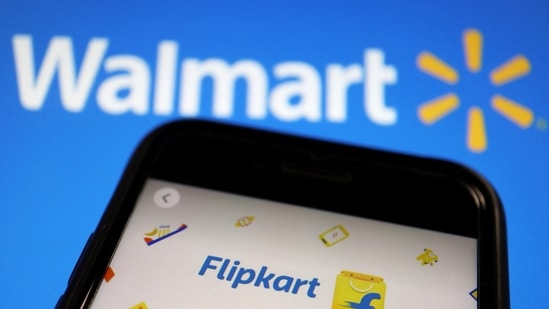 Latest news on August 16, 2024: A mobile phone showing an image of Indian online retailer Flipkart is seen in front of a Walmart Inc logo displayed.