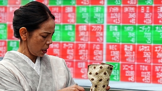 A person walks in front of an electronic stock board showing Japan's Nikkei index at a securities firm in Tokyo.(AP)