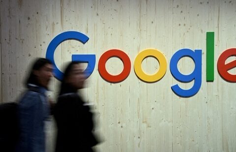 People walk next to a Google logo during a trade fair.(Reuters)