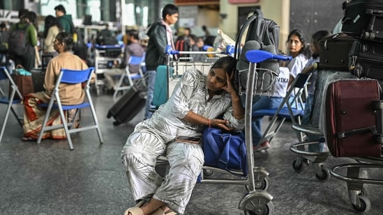 A passenger waits outside the IndiGo Airlines kiosk at the Kempegowda International Airport in Bengaluru on 6 December. (AFP)