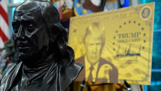 A bust of Benjamin Franklin, one of the founding fathers of the US, near a poster for the Trump Gold Card in the Oval Office of the White House (AP)