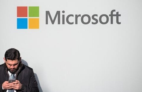 A man uses a phone next to a Microsoft logo during the 56th annual World Economic Forum meeting, in Davos, Switzerland, on 20 January 2026. (Reuters)