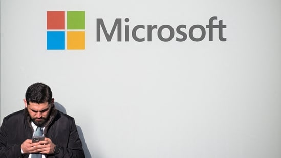 A man uses a phone next to a Microsoft logo during the 56th annual World Economic Forum meeting, in Davos, Switzerland, on 20 January 2026. (Reuters)