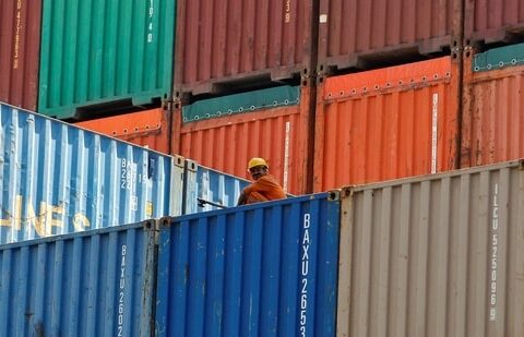 A worker sits on a ship carrying containers at Mundra port in Gujarat. (Reuters)