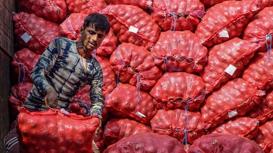 A worker unloads sacks of onions from a truck, at a wholesale vegetable market in Jalandhar (PTI)