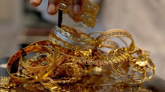 A goldsmith weighs gold jewellery inside a showroom in Ahmedabad, India. (REUTERS)