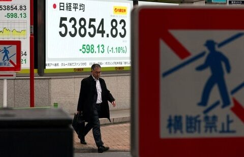 A man walks past a screen displaying Japan's Nikkei share average outside a brokerage in Tokyo, Japan. (REUTERS/File)