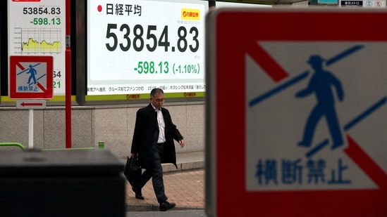 A man walks past a screen displaying Japan's Nikkei share average outside a brokerage in Tokyo, Japan. (REUTERS/File)