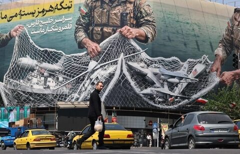 Vehicles drive past a giant billboard reading 'The Strait of Hormuz remains closed' at the Revolution Square in Tehran on April 28, (AFP)