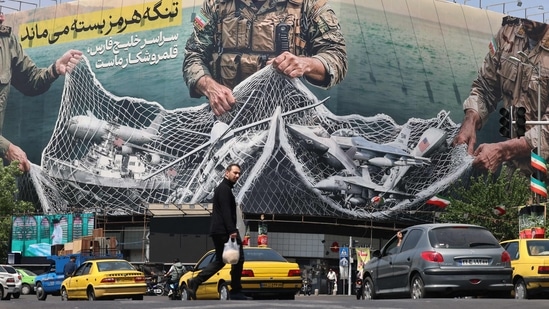Vehicles drive past a giant billboard reading 'The Strait of Hormuz remains closed' at the Revolution Square in Tehran on April 28, (AFP)