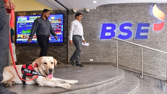 Sensex jumps over 300 points at open as markets rebound after Monday’s selloff A security personnel with a sniffer dog keeps vigil as people walk out of the Bombay Stock Exchange building in Mumbai. (PTI)