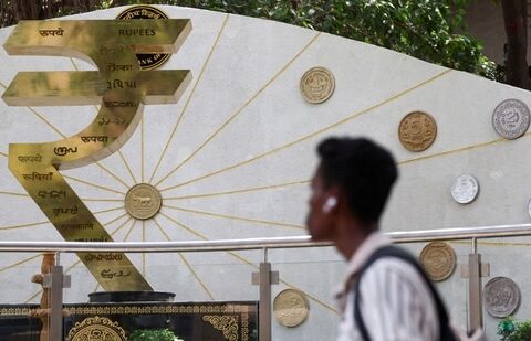 A man walks past an installation of the Rupee logo and Indian currency coins outside the Reserve Bank of India (RBI) headquarters in Mumbai (REUTERS)