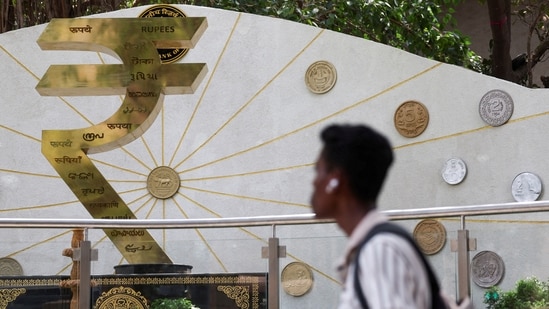 A man walks past an installation of the Rupee logo and Indian currency coins outside the Reserve Bank of India (RBI) headquarters in Mumbai (REUTERS)