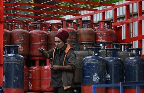 A delivery worker stands atop a truck carrying LPG cylinders at a distribution point in Bengaluru. (AFP)