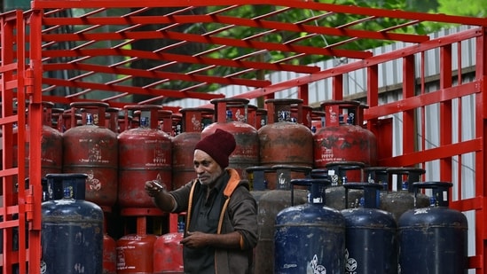 A delivery worker stands atop a truck carrying LPG cylinders at a HP Gas distribution point in Bengaluru. (AFP)
