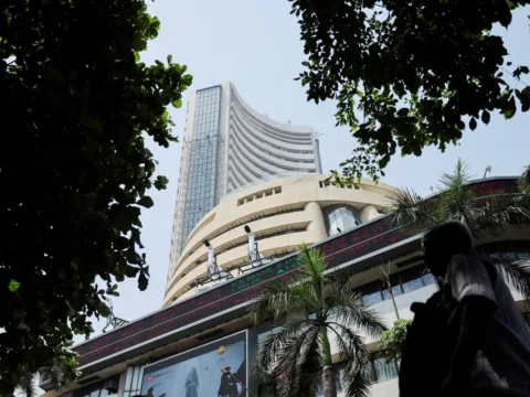 Men walk past a screen displaying market results outside the Bombay Stock Exchange (BSE) in Mumbai. (REUTERS)